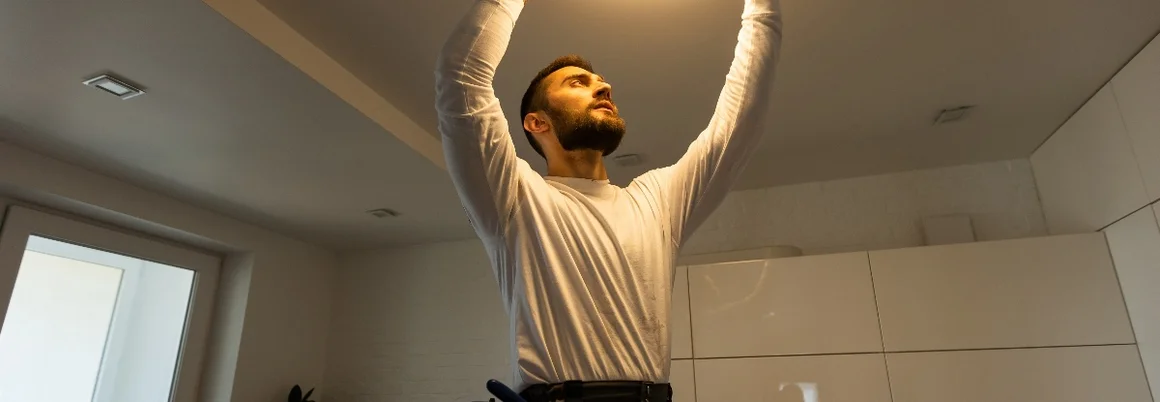 Person bringt eine Deckenleuchte an